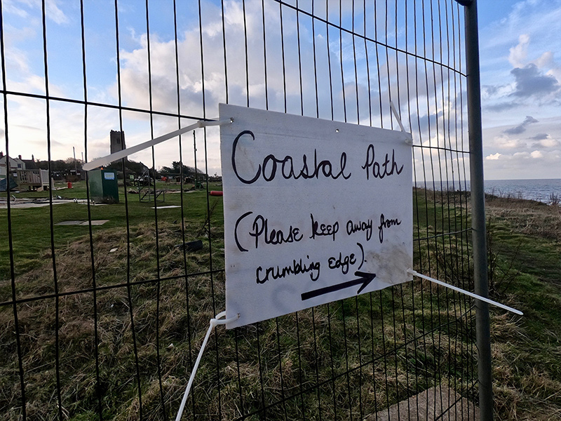 A sign that reads ‘Coastal Path (please keep away from the crumbing edge)’ near Happisburgh