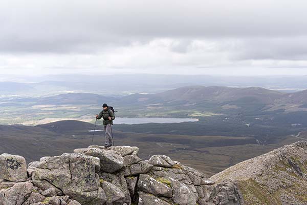 hiking poles for beginners - a man with poles on the summit of a mountain
