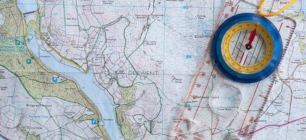 Compass on an OS map with ruler for measuring map distance