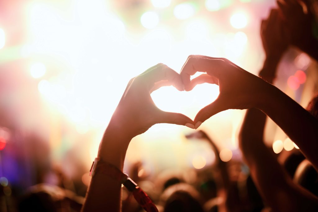 lattitude_alt-tag-a-heart-shape-on-a-festival-dancefloor-made-from-two-hands-held-together-with-the-thumb-and-index-fingers-touching.-adobestock_200128362-scaled.jpeg