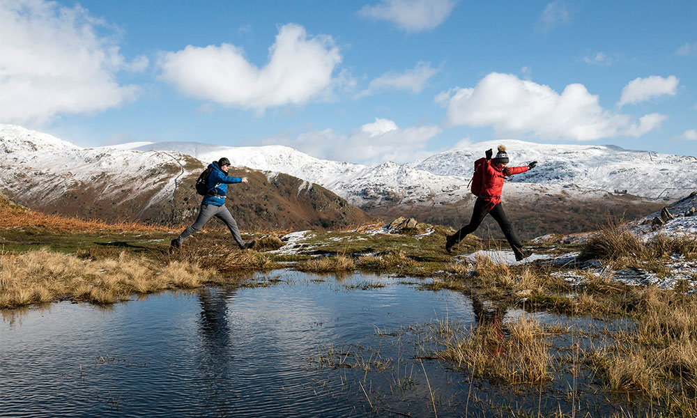 Hikers crossing mountain lake winter