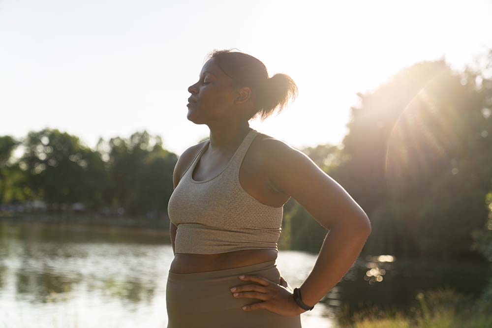 Young African American woman breathing after hard workout at the park