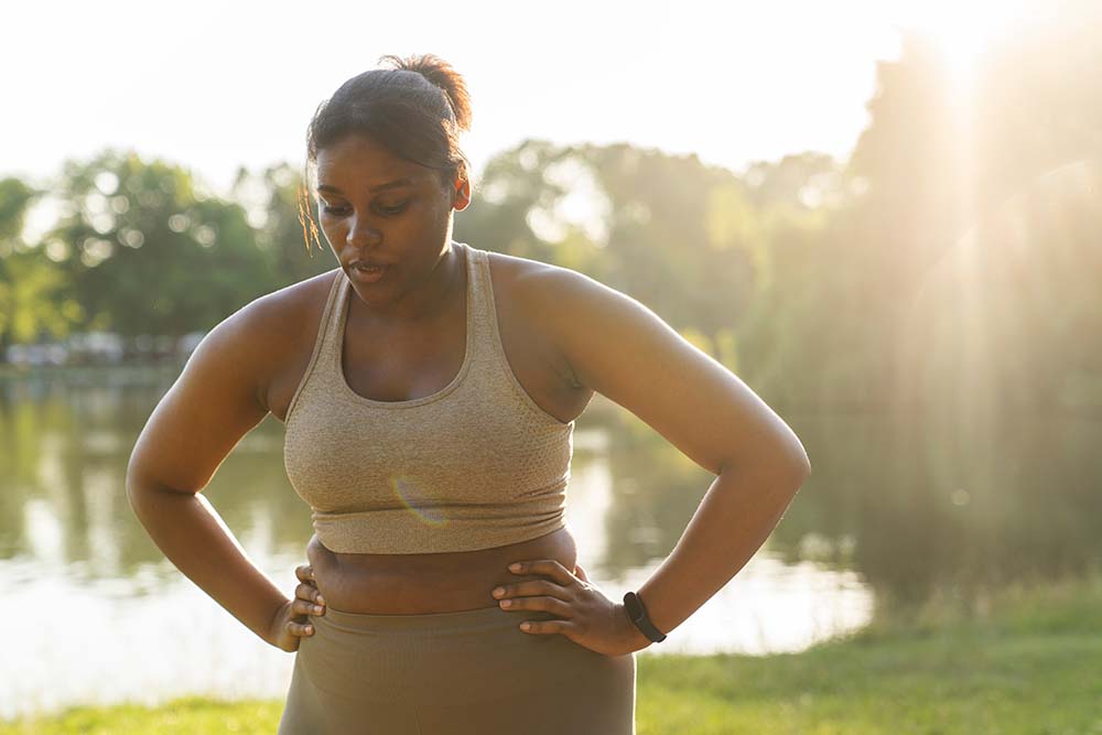 Young African American woman breathing after hard workout at the park
