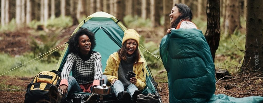 friends camping and laughing in the woods