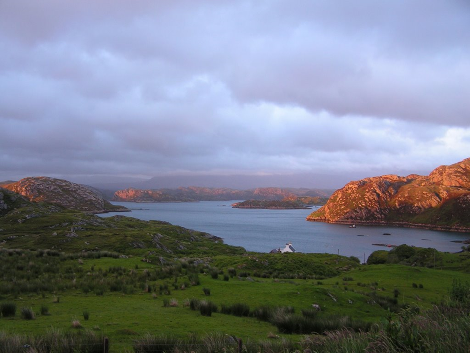 a cottage in the distance with a beautiful coastline