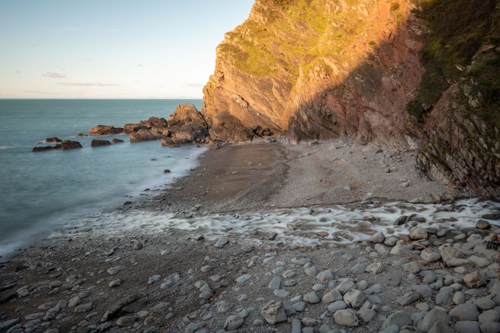 Long exposure of the river Heddon flowing onto the beach at Heddons Mouth in Exmoor