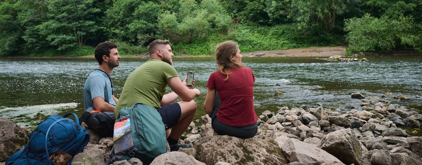 Group of people next to a river checking location using OS Maps app