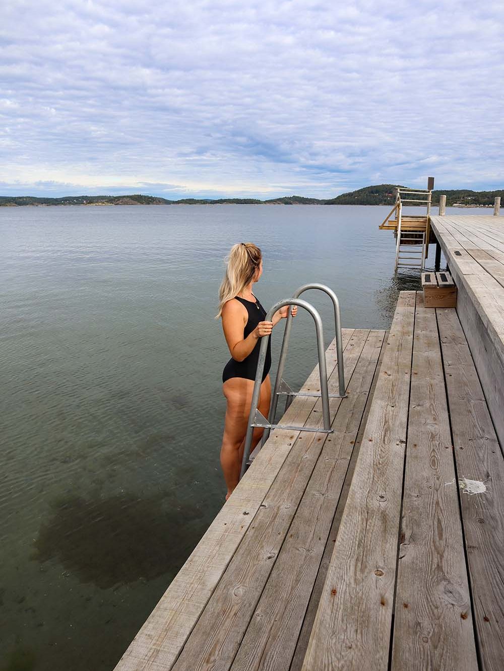 sophie climbing down a ladder from a jetty for a swim