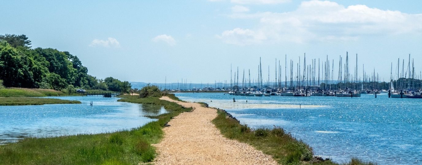 The Solent Way footpath with yachts in the distance and woodland to the left