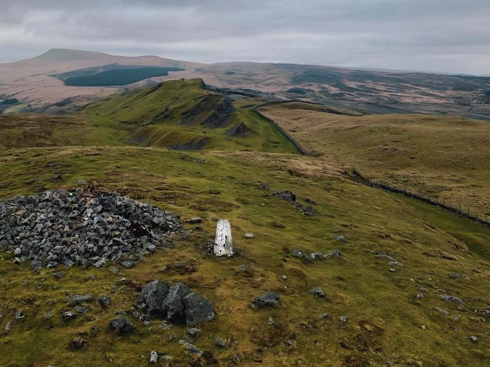 a trig point standing alone in a hillscape