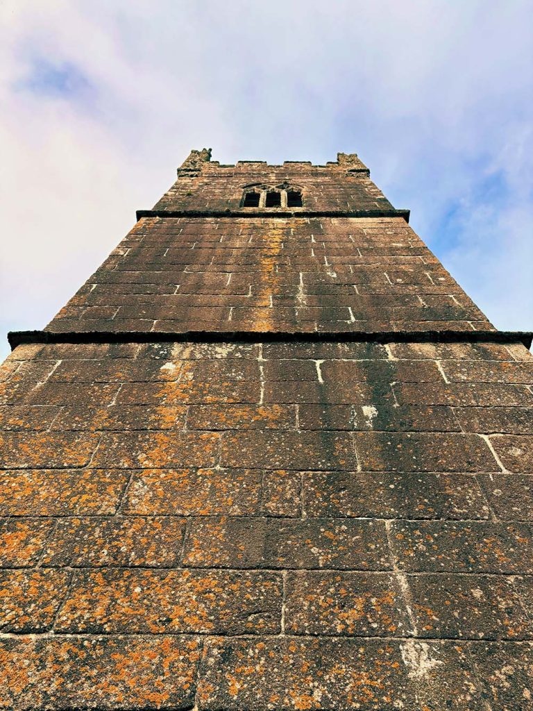 View looking up at a tall stone tower against a cloudy sky.