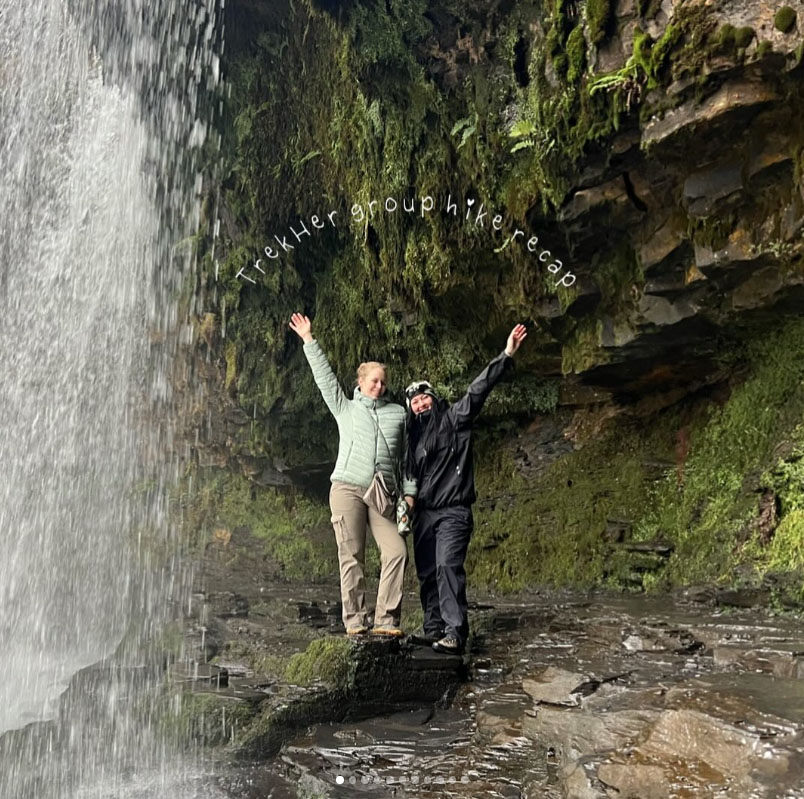 Two people standing under a waterfall