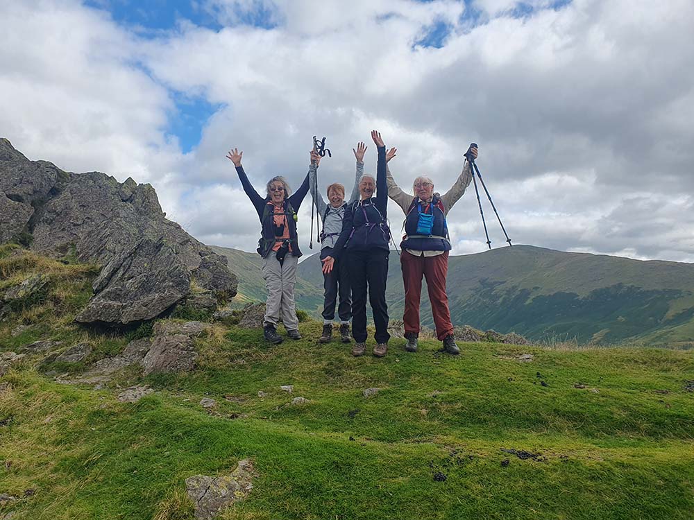 women celebrating with their arms outstretched on a hike