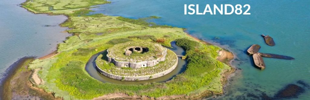 aerial picture of an island with green grass and bright blue sea