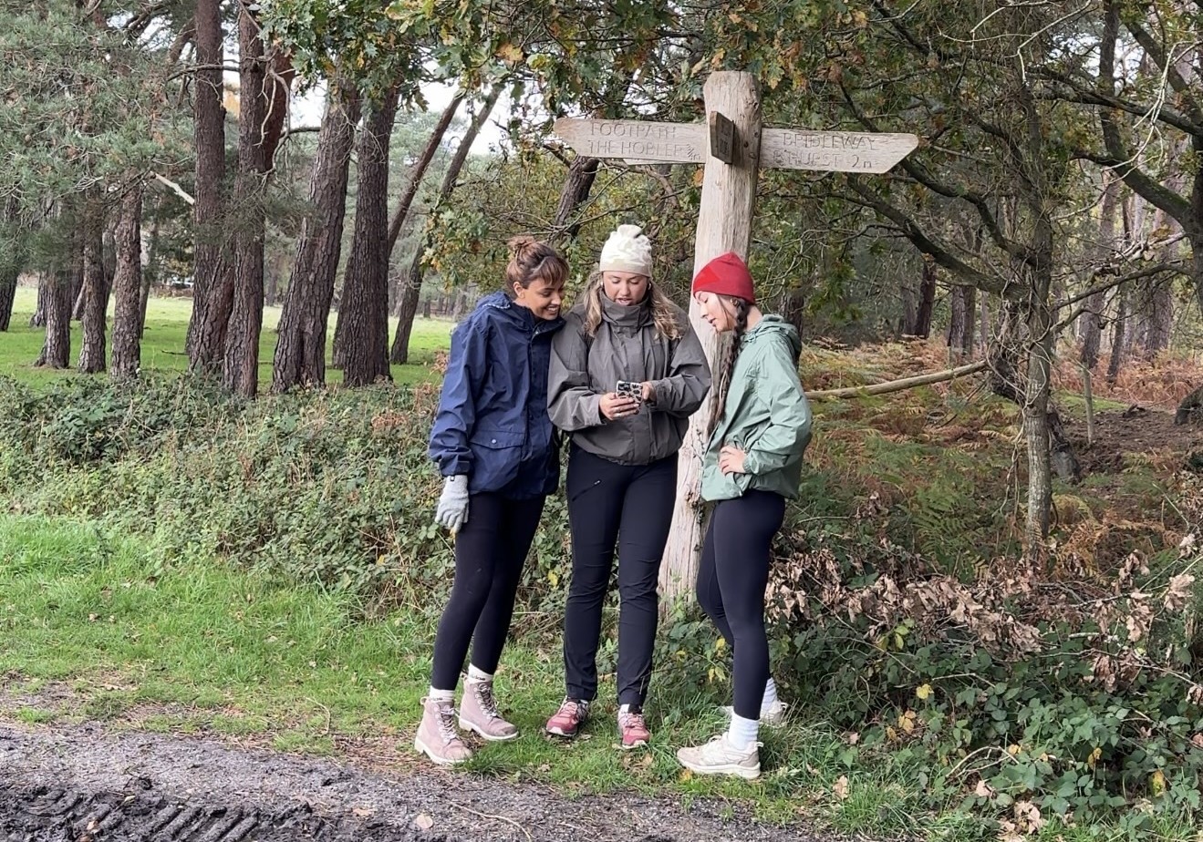 friends looking at OS Maps App by a finger post