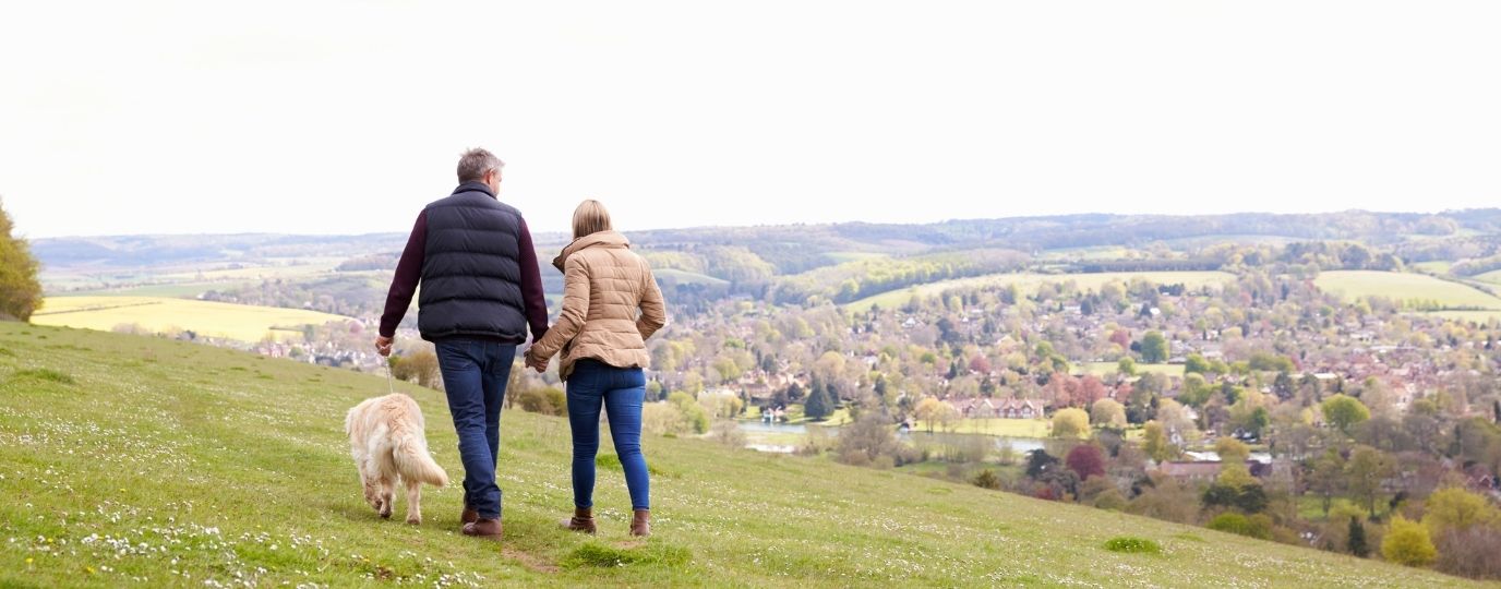 a couple walking the dog on a hill