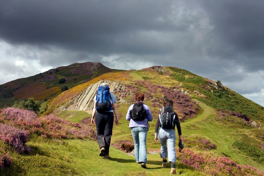 3 women on a hike heading up to a cloudy summit