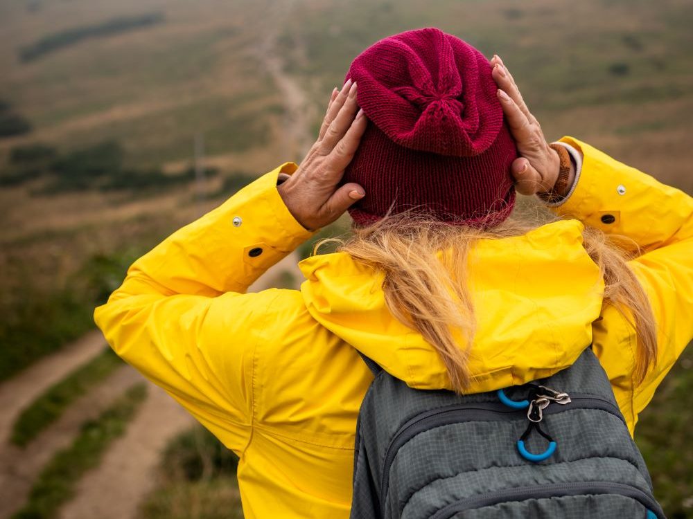 woman clutching her woolly hat in the wind