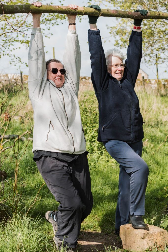 two women holding onto a tree branch