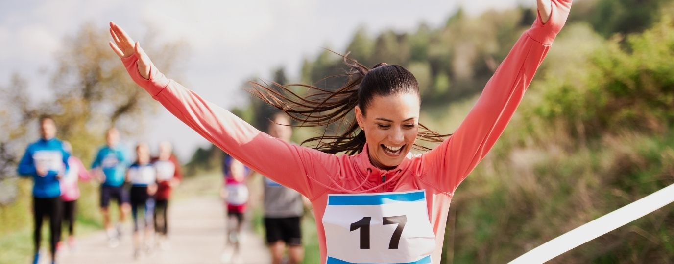 a woman in pink crossing the finish line