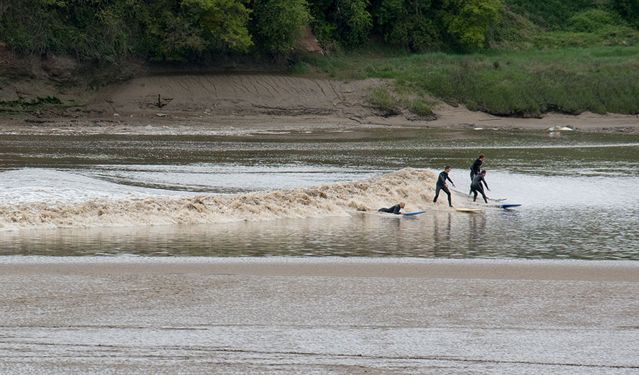 Surfers ride the Severn Bore tidal wave at Newnham-on-Severn, Gloucestershire