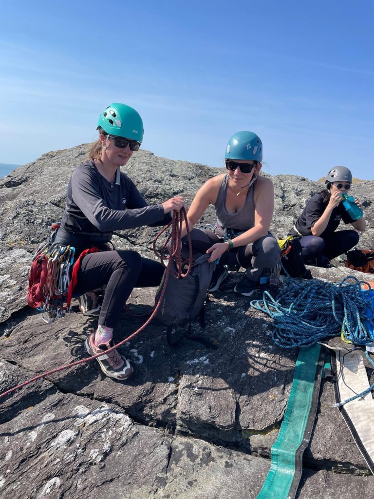 women in helmets with rock climbing ropes