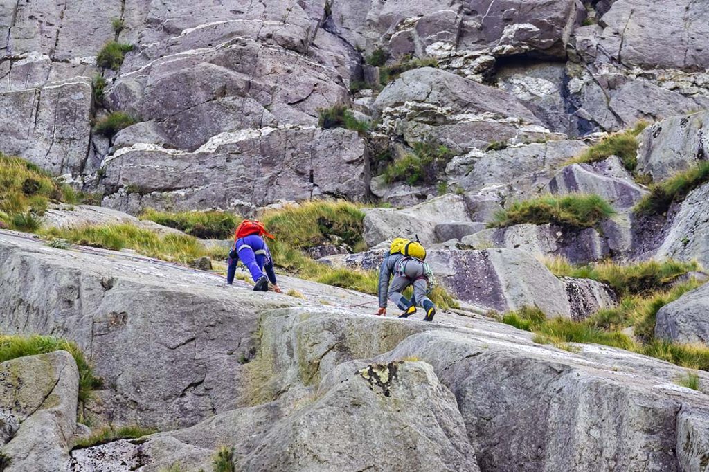 Two climbers make their way up a sloped rock face