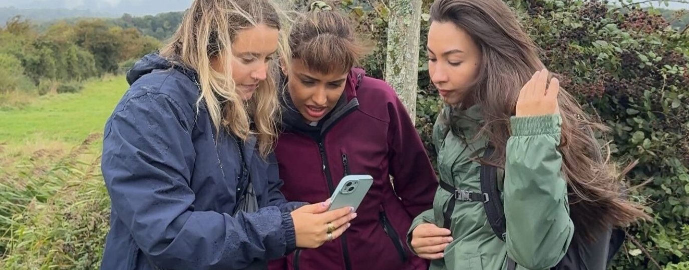 3 women looking at os maps app on a phone outside