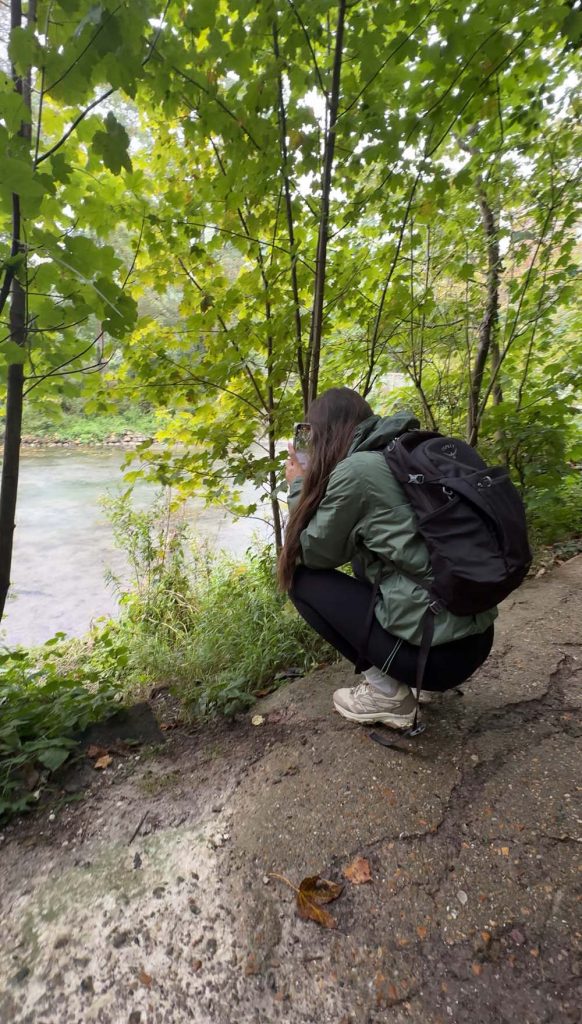 a woman kneeling taking a photo of wildlife on a river