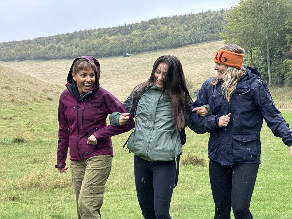 3 women walking down a hilly field